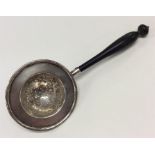 A Continental silver tea strainer with turned ebony handl