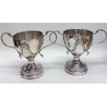 A pair of unusual silver loving cups decorated wit