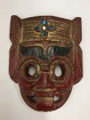 A red lacquered tribal mask decorated in bright co