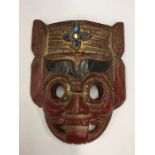 A red lacquered tribal mask decorated in bright co