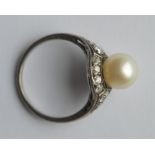 A pearl and diamond ring with large central stone.