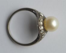 A pearl and diamond ring with large central stone.