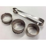 A group of four silver napkin rings together with