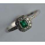 An attractive platinum, emerald and diamond cluste