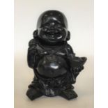 A carved wooden figure of Buddha carrying a loaded
