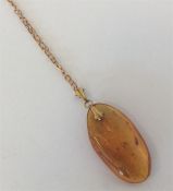 A small amber single stone pendant on fine link ch