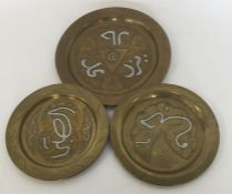 A set of three Eastern brass plates decorated with