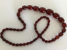 A graduated string of cherry amber beads. Approx.