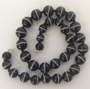 A graduated string of banded agate beads. Approx.