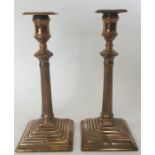 A pair of unusual brass candlesticks on step bases