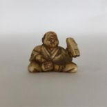 A small carved ivory netsuke in the form of a cros