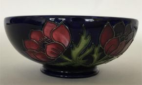 MOORCROFT: A blue-ground shallow bowl decorated wi
