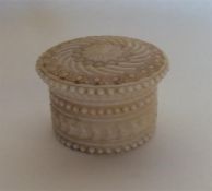 A small circular Antique ivory box decorated with