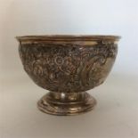 A small embossed silver sugar bowl decorated with
