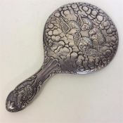 A heavy silver hand mirror attractively decorated