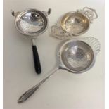 A group of three silver tea strainers decorated wi