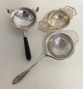 A group of three silver tea strainers decorated wi
