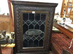 An oak lead glazed carved corner cupboard.