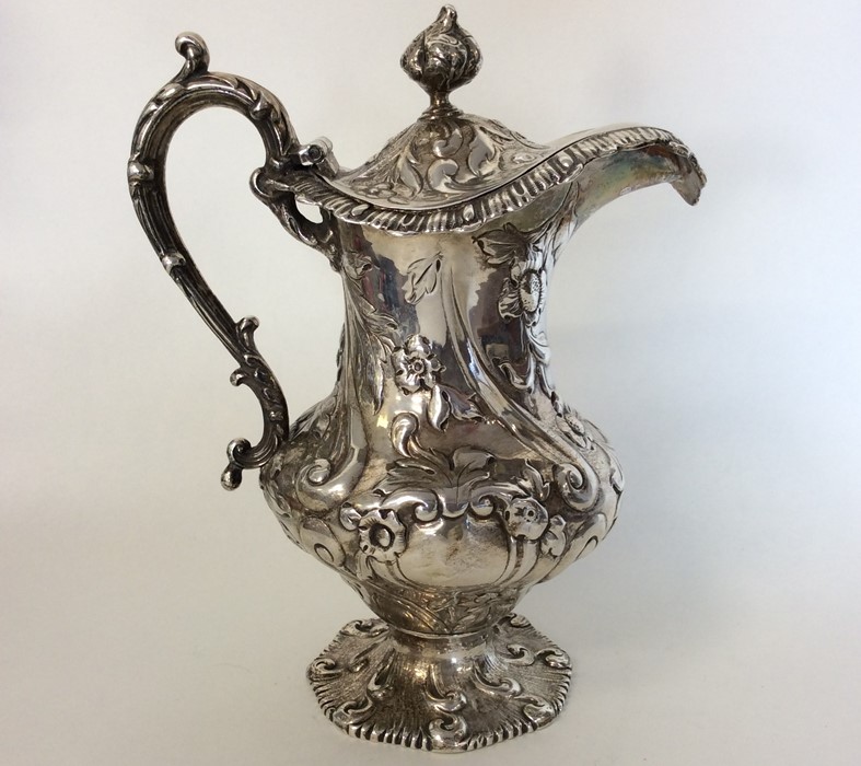 A Victorian silver embossed jug with hinged cover