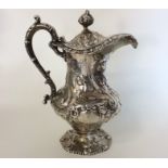 A Victorian silver embossed jug with hinged cover