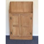 A stripped pine two door cupboard with shaped top