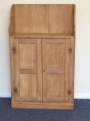 A stripped pine two door cupboard with shaped top