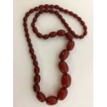 A graduated string of red amber beads. Approx. 77