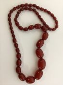A graduated string of red amber beads. Approx. 77
