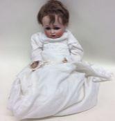 A German porcelain headed doll dressed in christen