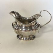 A silver cream jug with wavy edge to flat base. Bi