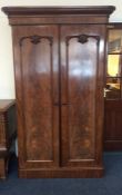 A mahogany two door wardrobe decorated with scroll