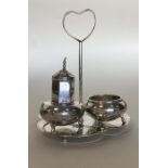 A silver Egyptian style cruet mounted on a tray wi