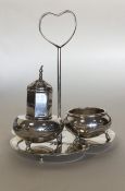 A silver Egyptian style cruet mounted on a tray wi