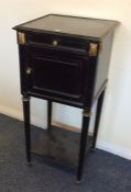 An ebony and gilded pot cupboard on tapering legs