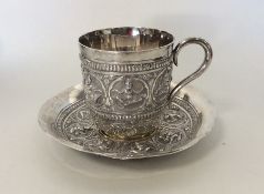 A heavy Indian silver cup with matching saucer, he