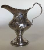 A Georgian silver cream jug decorated with flowers