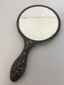 An attractively embossed silver hand mirror decora