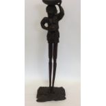 A tall carved tribal figure with textured body. Ap