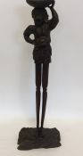 A tall carved tribal figure with textured body. Ap