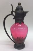 A good ruby glass claret jug with pewter mounts an