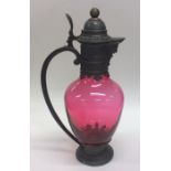 A good ruby glass claret jug with pewter mounts an