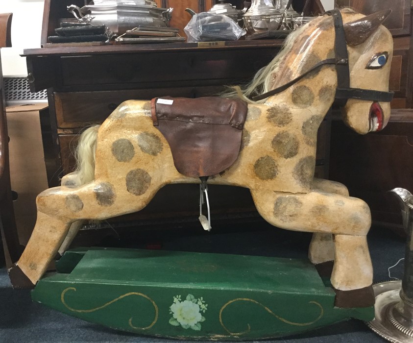 A wooden painted rocking horse with leather seat.