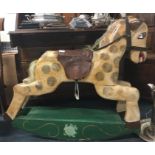 A wooden painted rocking horse with leather seat.