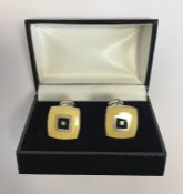 A pair of silver and enameled cufflinks in fitted