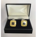 A pair of silver and enameled cufflinks in fitted