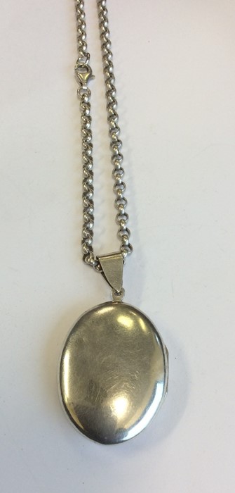 A heavy silver oval locket on fine link chain. App