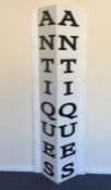 A large metal sign for "Antiques" in white with bl