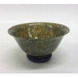 A small circular jade tea bowl on hardwood base. E