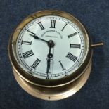 A brass mounted marine wall clock with white ename