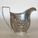 A small silver embossed cream jug with reeded deco